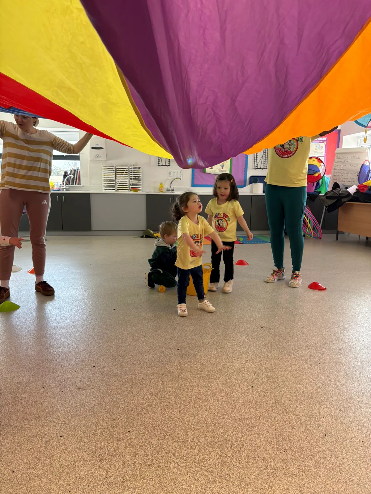 Children playing together beneath a colourful parachute