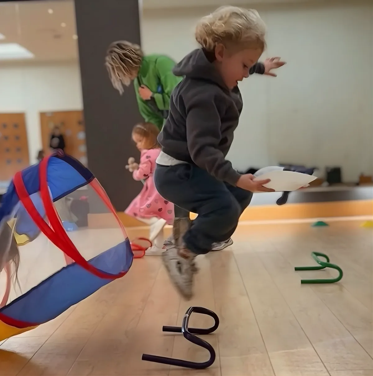 A Track Totter jumping over a hurdle beside a play tunnel